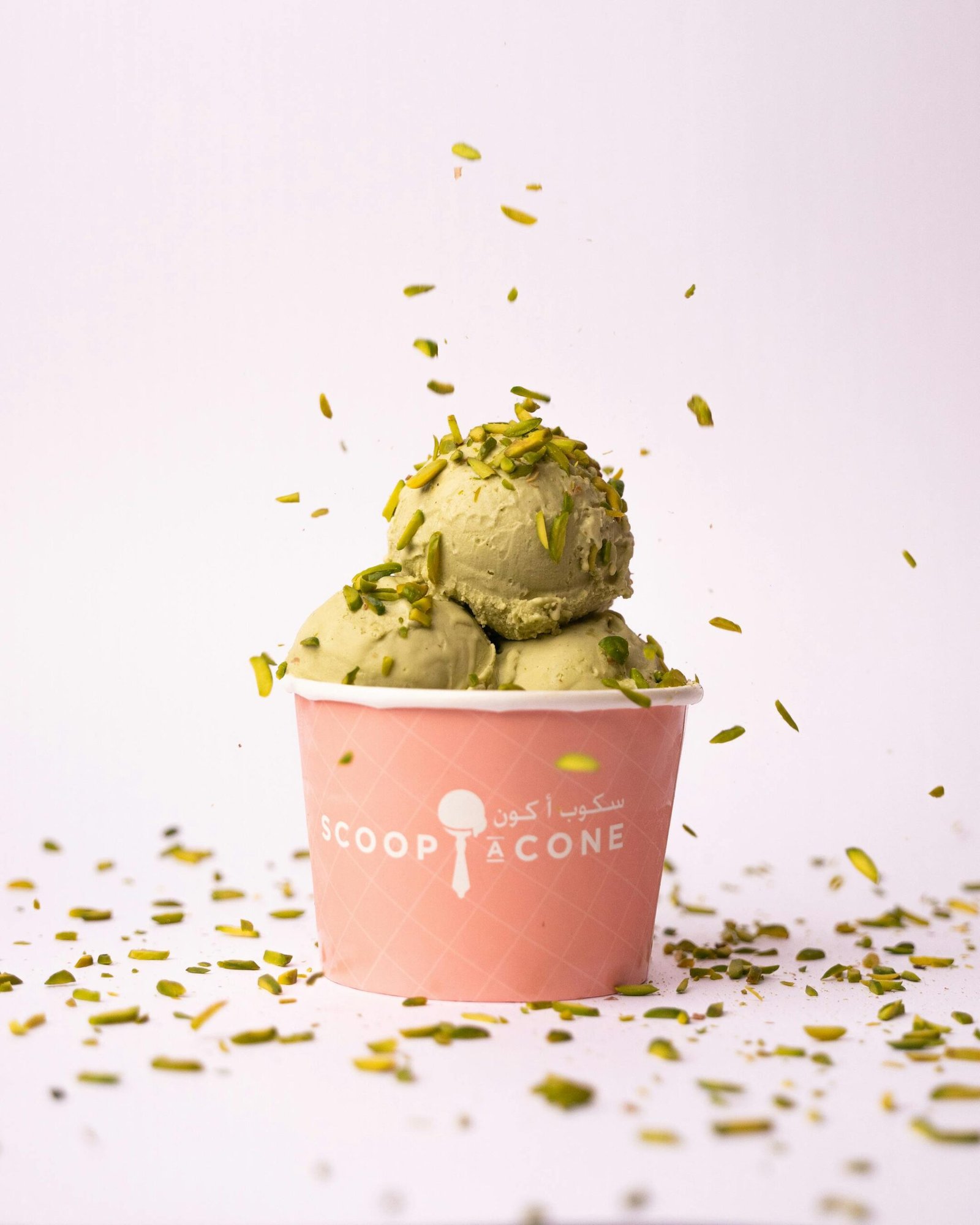 A sprinkle of pistachio enhances this creamy ice cream treat in a pink cup.